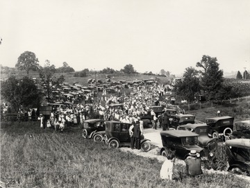 Celebration of completion of a highway project.  The picture features a crowd and numerous parked automobiles in the vicinity of a highway through a rural area in north central West Virginia.