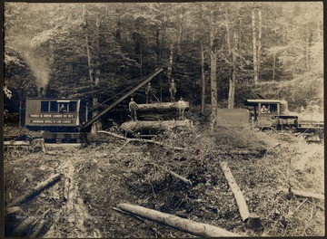 Log Loader and train engine transporting lumber. Four men standing on logs.