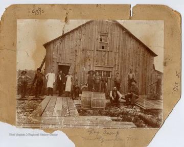 Men posed in front of a wooden building.