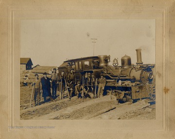 Men pose beside and inside a log train.  