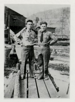 Two men standing on lumber at a log pond.  Original from Paul James.