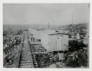 Camp beside a railroad.  Men working around camp area.  