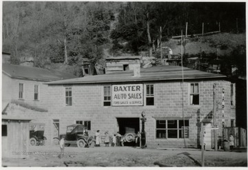 Front view of Baxter Auto Sales.  People and automobiles in front of the building.  