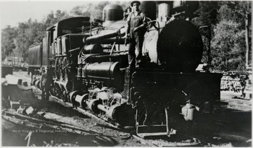 3/4 front view of Shay train engine with man standing on the front end.