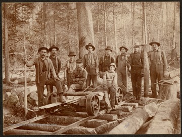 Group portrait of loggers standing on railroad tracks.