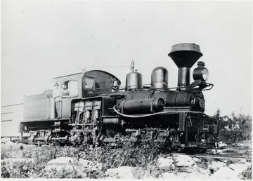 Shay train engine.  Construction camp.  At throttle:  Charlie Crommer.  In doorway:  Unknown
