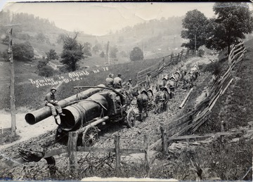 Team of eight horses pulling oil equipment up a muddy hill.  