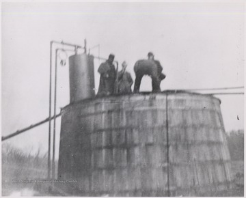 Men standing on top of an oil tank