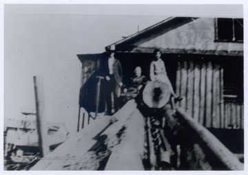 Three crew members at the log slide at the lumber mill.