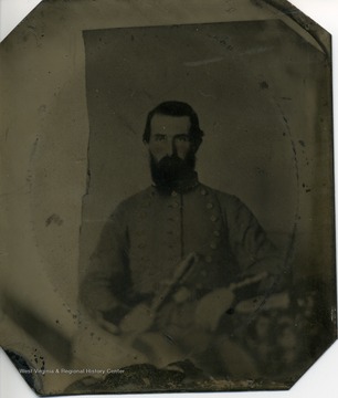 Bearded man wearing a dress uniform with dark trim, of a Confederate officer, and holding a sword.