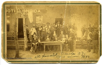 This picture was taken in Oneida N.Y. in 1880. These glass workers are all from the Durbanville factory. Sitting down from left to right are: Charles Boudon, Adrian Boudon, Robert Andris, Edward Andris, Victor Lang, Mr Dichano, Edward Andris.  4th from left; sitting at table with mark on face is Grandfather of Leo Wery of Henryetta, Floyd Wery of Ft. Smith and Chas. Wery of Shreveport. This was Mr. Myers bar of Oneida.  The other names are unknown but are all glass workers of the Durbanville factory.
