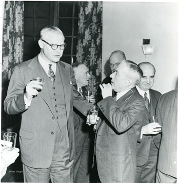 Two coal officials with drinks talking.