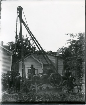 Men pose by drilling equipment. 'Rig possible owned by O. C. Carter.'