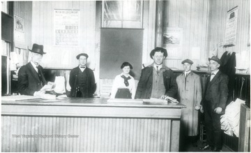 'Interior of Chesapeake [and] Ohio Railroad Freight Depot at Alderson W. Va. At extreme left, behind counter is the station agent T.L. Dameron and standing on extreme right is freight agent W.A. Hancock (who worked in the Alderson station for fifty years. He was a deaf-mute.)'