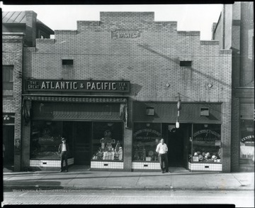 Outside view of The Great Atlantic and Pacific Tea Co. Grocery Store in Grafton, W. Va.  Two men standing in front of the entrances.