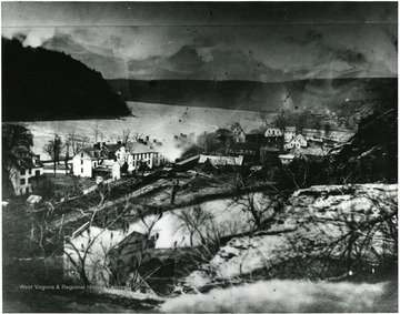 A Winchester and Potomac Railroad train carrying Federal Troops passes through Virginius Island at Harpers Ferry, West Virginia. The shell of the Abraham Herr Mill, burned by Confederate soldiers in 1861, can be seen in the center of the photograph.