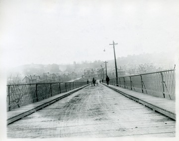 A horse-drawn carraige and people are crossing the South Park Bridge in Morgantown, West Virginia.