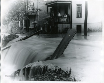 Townspeople are watching the Falling Run Flood from their University Avenue front porch in Morgantown, West Virginia.