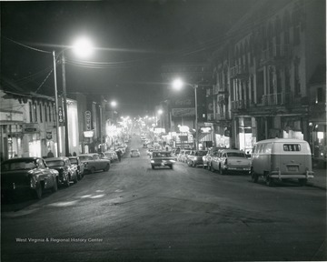 'North High Street looking South'. Taken after dark and the street lights are illuminated. Lights from stores and cars shine as well. 