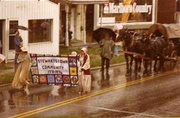 Two women carry the Stewartstown Community Banner in the Rain.