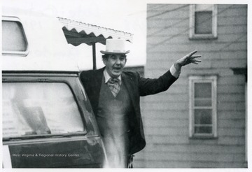A. James Manchin waves from the back of a vehicle.  