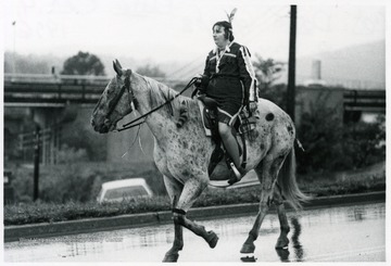 A woman dressed like an Indian rides a horse in the parade.
