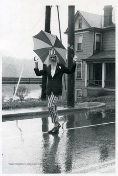 A man dressed as Uncle Sam walks down Beechurst Avenue with an umbrella and a small American flag.