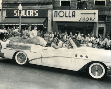 Two young ladies representing local labor unions ride in the back of a convertible in a parade. 