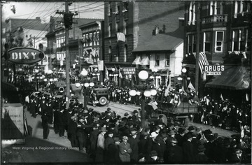 People gather to see the Armistice Day Parade on High Street.  Parade participants riding in a truck with American flags.