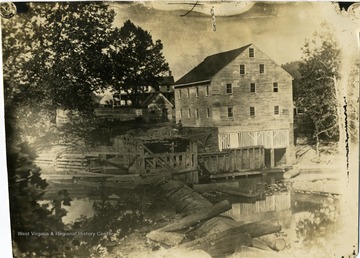 A view of Jackson's Mill with a man beside the building. 'Photo by or for Sam Barret.'