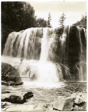There is a woman on a diving board beside the falls.  'Photograph by courtesy of United States Forest Service.'