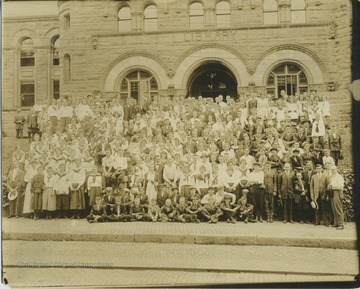 A group of women, men, and children, who are likely members of a 4-H group. The group is in front of the library, which is now Stewart Hall.