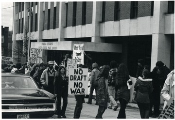 Female with 'Stop the Draft' sign is Alice Bell.