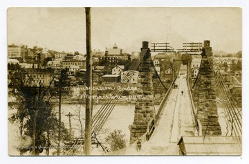 A view of the Old Suspension Bridge: pedestrians and a buggy going by.