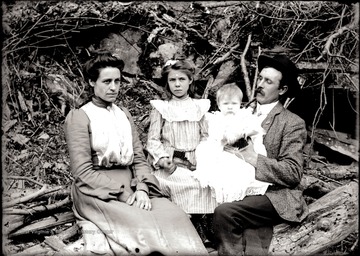 Man and woman with two children seated outdoors for a portrait.