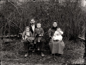 Man, woman, and three children seated outdoors for a portrait.