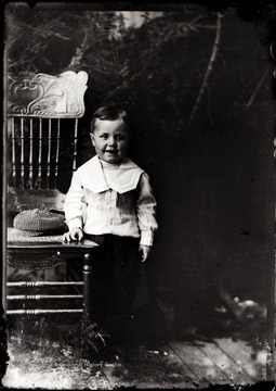 A portrait of smiling boy leaning against a chair taken indoors in Helvetia, W. Va.
