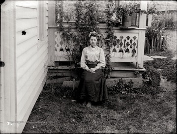 A portrait of seated young woman just outside of the porch in Helvetia, W. Va.