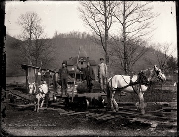 Loggers on horse drawn train carts.