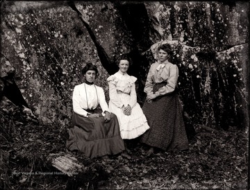 A portrait of three women sitting right at rock ledges.