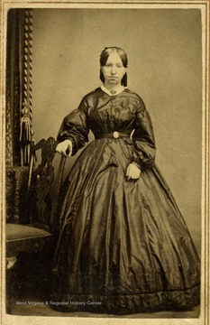 The style of the dress and hair indicates this photograph was taken in the 1860's. The young woman is not identified.