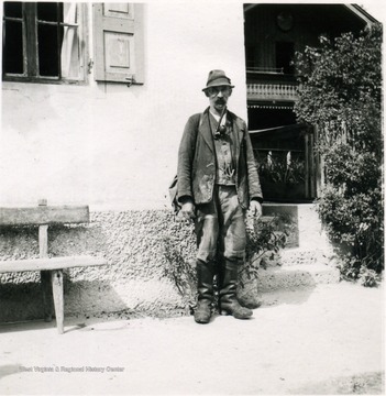 Unidentified man dressed in laborer's clothes, including sturdy boots. This photograph was taken approximately three months after Germany surrendered. Note the unusual pipe the man has in his mouth.