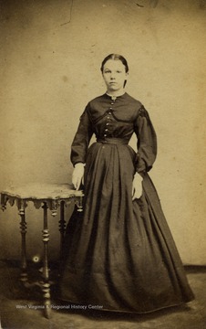 A carte de visite of a young woman wearing Civil War period fashion and hair style. There is also a revenue stamp on the back of the photograph with the date "July 24, 1866".