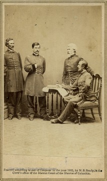 A carte de visite image of Union General George B. McClellan and his staff, left to right: Captain Clark, General McClellan striking a napoleonic pose, Captain Van Vliet and Major Barry. Information printed on the bottom of image: "Entered according to Act of Congress in the year 1862, by M.B. Brady, in the Clerk's office of the District Court of the District of Columbia."