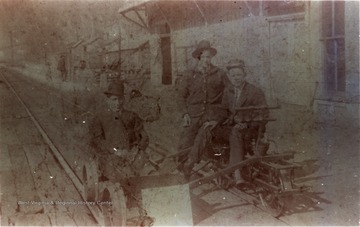 Three unidentified men seated on a velocipede at the Chesapeake &amp; Ohio (C&amp;O) Depot and Telegraph Office in Prince, West Virginia. "J. S. Sampson Collection"