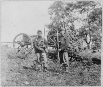 Two unidentified soldiers of the 22nd New York State Militia, Union Army, in full uniform and armed, standing in front of a caisson. Note the caisson carries a spare wheel.