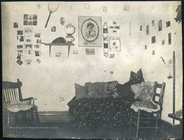 Dorm room walls decorated with photograph, posters and a tennis racket.