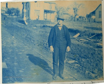 Unidentified young man stands on a brick paved road.