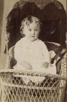 Toddler in a lace dress. Could be a boy or girl since very young boys wore dresses also. 