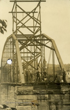 Unidentified workmen stand on stone piers during construction on the Grantsville Bridge.